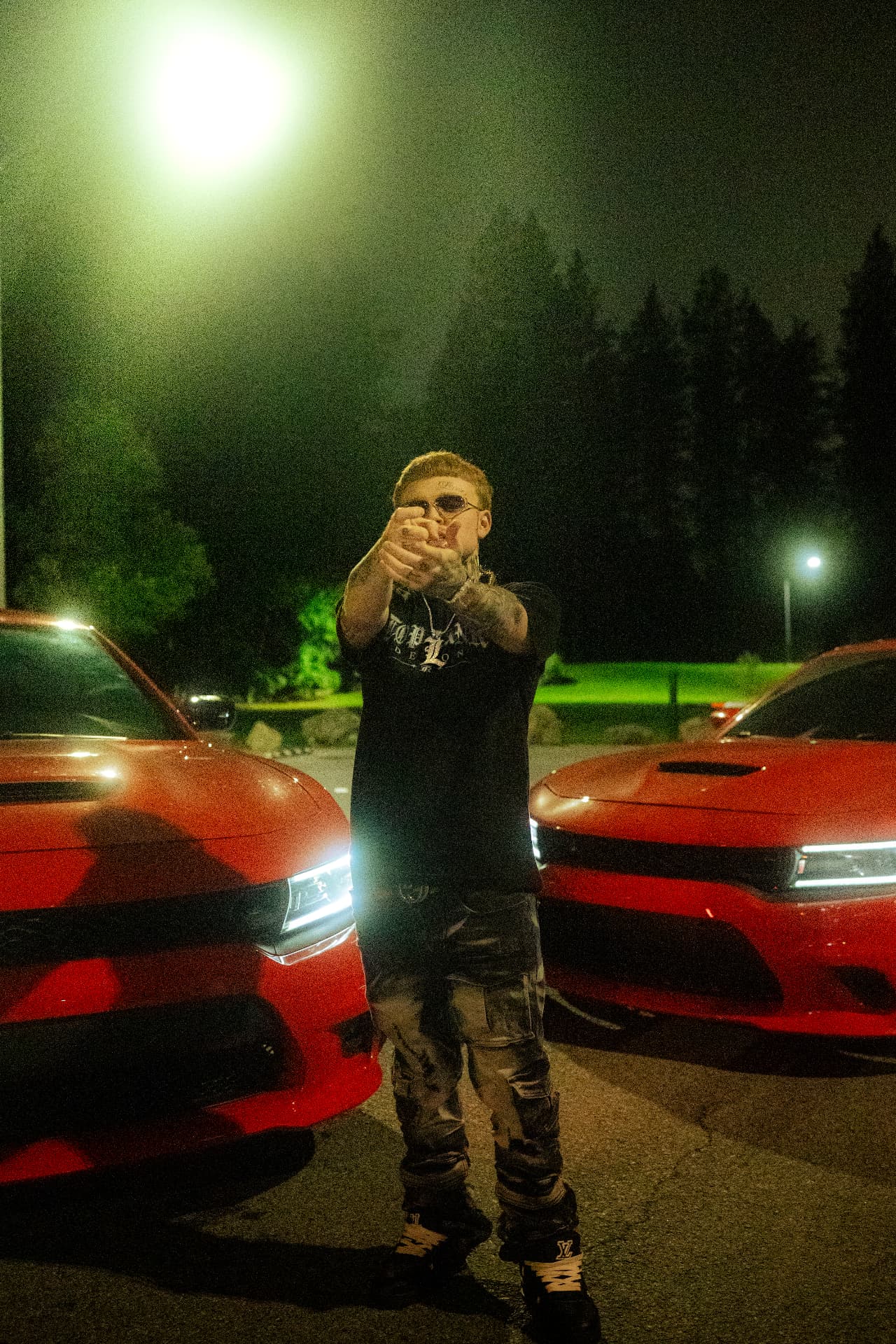 1TopRankDemon4 wearing the TOPRANKDEMON LUXURY TEE between two red cars